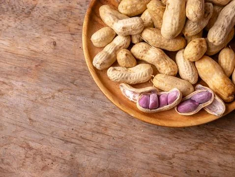 Boiled peanuts in shell with purple violet skin kernels revealed on wooden .. Stock Photos