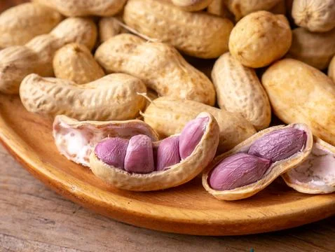 Boiled peanuts in shell with purple violet skin kernels revealed on wooden .. Stock Photos