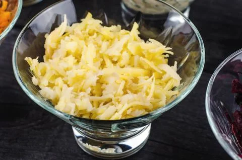 Boiled potatoes crushed in a transparent deep dish on a wooden black backgrou Stock Photos