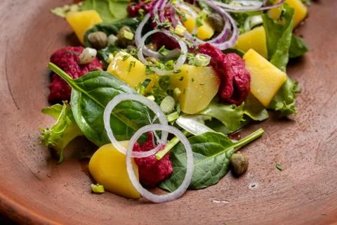 Boiled potatoes with dill and beetroot paste. Sprinkled with onions and capers. Photos