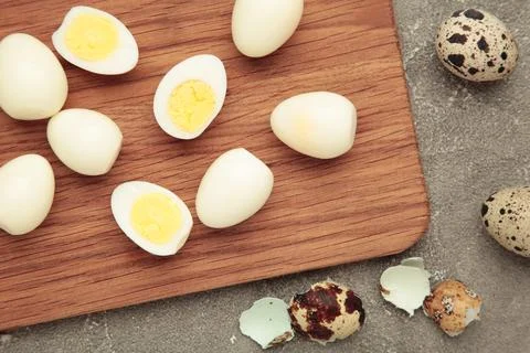 Boiled quail eggs on cutting board on grey concrete background. Easter Stock Photos