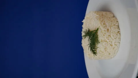 Boiled rice in a rotating plate on a blue background. Ready dish Stock Footage 163903839