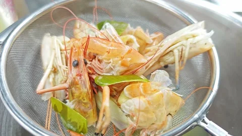 Boiled river prawn heads and herbs draining in a metal strainer. Stock Footage 342394357