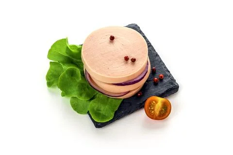 Boiled sausage eats on a black slate plate with lettuce, spices and tomatoes. Stock Photos