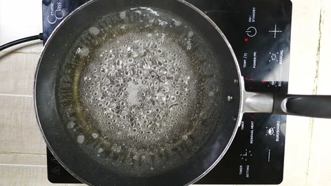 Boiled water with bubble in teflon pan with smoke,red light indicator power o Stock Footage 128941795