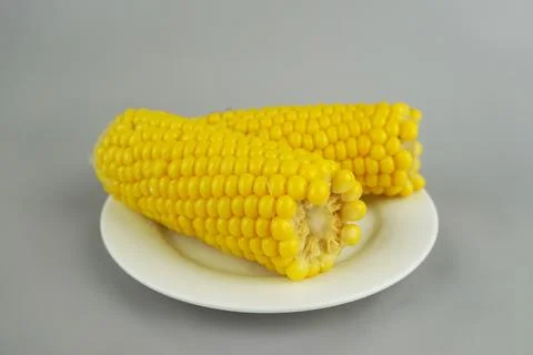 Boiled yellow corn cobs on a white plate isolated on gray background, fresh.. Foto stock