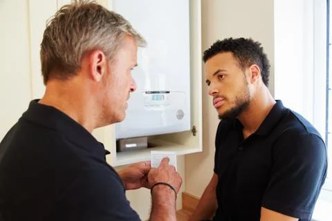Boiler technician and apprentice servicing domestic boiler Stock Photos
