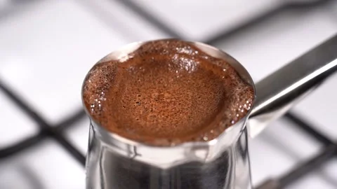 Boiling and overflowing coffee while preparation in turkish coffee pot Stock Footage 145265437