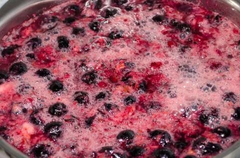 Boiling black currant and raspberry compote Stock Photos