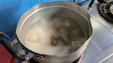 Boiling bone broth soup in pot at gas stove at kitchen at home point of view Stock Footage 277213810