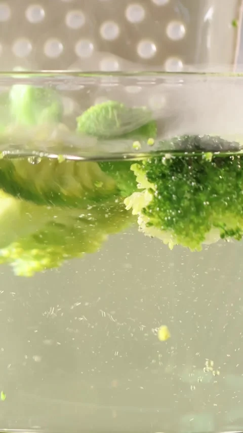 Boiling broccoli in a glass pot on a kitchen stove with steam 動画素材 345426531
