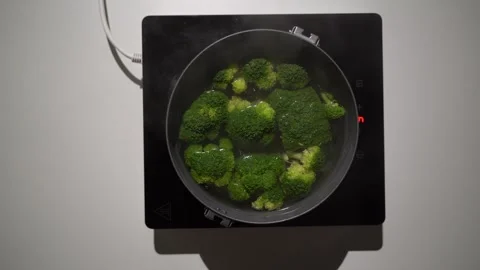 Boiling broccoli in a pot on small Induction Cooktop. Stock Footage 256931958