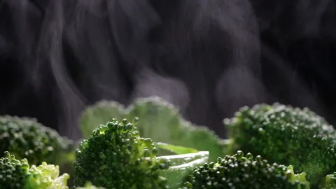 Boiling broccoli with steam in slow motion. Cocking broccoli on black background Stock Footage 130617423