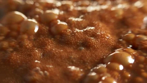 Boiling caramel. Macro shot of bubbles in boiling thick brown liquid, shallow Stock Footage 197119971