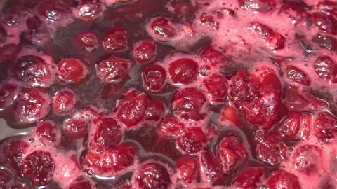 Boiling cherry jam with berries in dark syrup and foam in close up Stock Footage 337883266