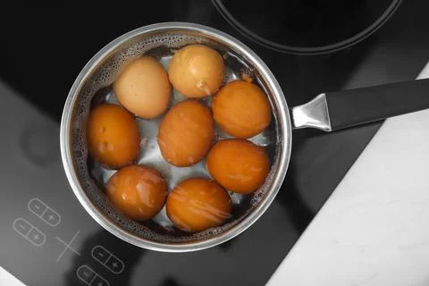 Boiling chicken eggs in saucepan on electric stove, top view Stock Photos