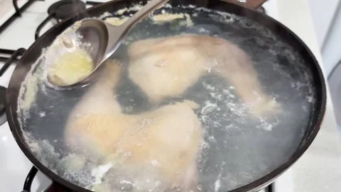 Boiling Chicken Legs in Pot While Ladle Skims Foam for Clear Broth Stock Footage 329664108