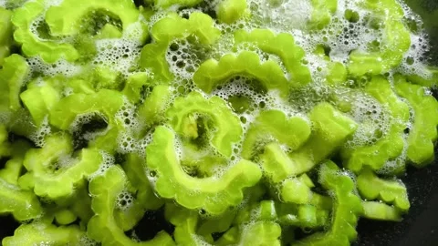 Boiling chopped bitter gourds in pan, in door  Chiangmai  Thailand. Stock Footage 308906550
