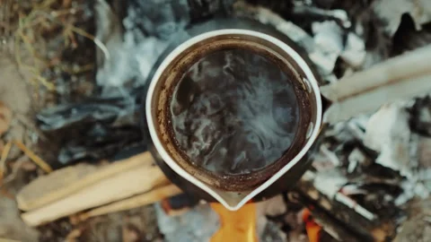 Boiling coffee on a fire in cezve coffee pot close-up Stock Footage 253408931