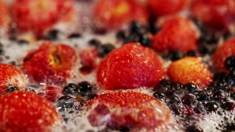 Boiling compote of fresh strawberries, red currants and blueberries in a Stock Footage 313892109