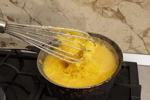 Boiling corn flour in a cast iron pot, making mamaliga, traditional romania.. Stock Photos