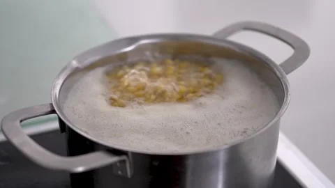 Boiling corn in a pot on the stove in a home kitchen Stock Footage 344186428