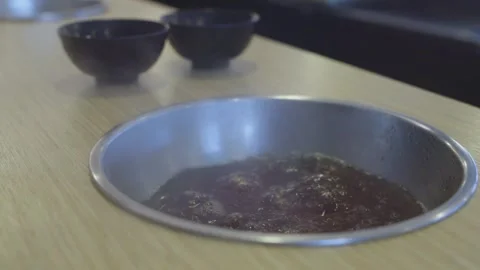 Boiling dark broth inside a metal pot recessed into a wooden table at a res.. Stock Footage 335939738