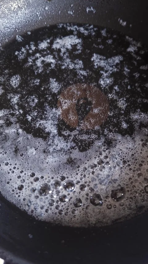 Boiling Dark Liquid with White Foam Bubbles Inside Hot Frying Pan Video stock 339081844