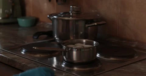 Boiling eggs and preparing for colorful designs in cozy kitchen. Metal pan on Stock Footage 306067057