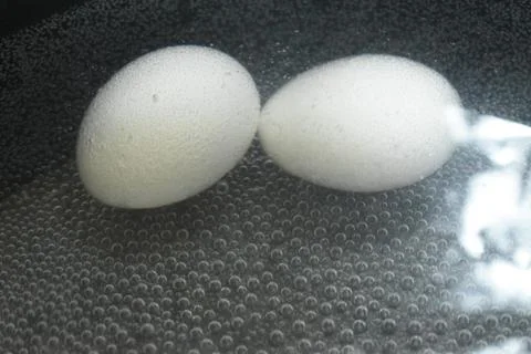 Boiling eggs in a bubble background with black pot. Stock Photos