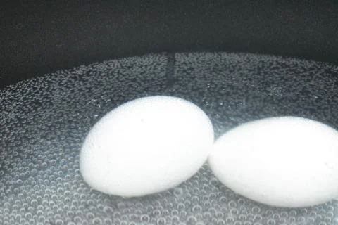 Boiling eggs in a bubble background with black pot. Stock Photos