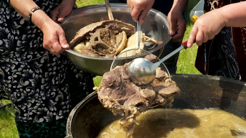 A boiling fatty broth with meat is fried and stewed in a cauldron. Video stock 328171067