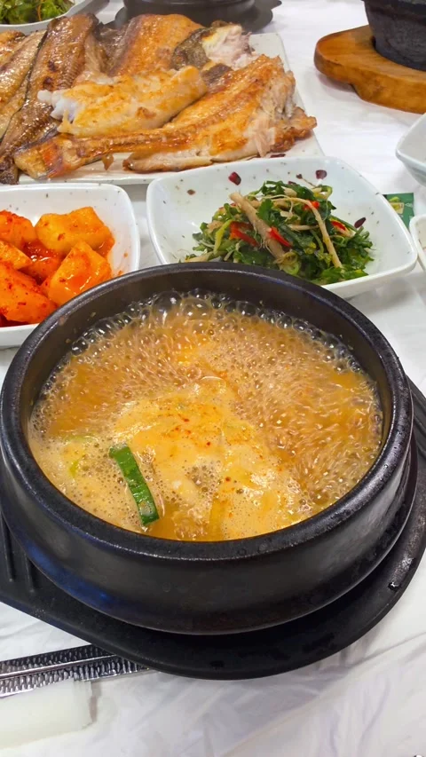 Boiling hot soybean paste stew in traditional earthenware pot with side dishes Stock Footage 326033116