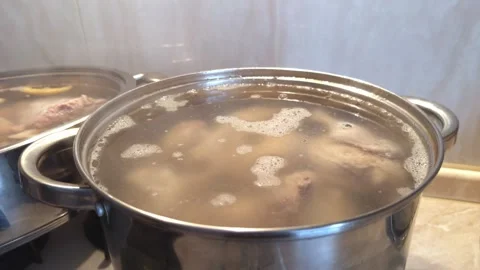 Boiling meat broth in a large pot on the stove, homemade soup cooking. Stock Footage 322220357