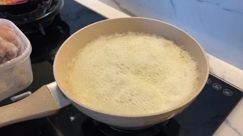 Boiling Milk in Ceramic Pan with Chicken Prep Nearby on Stove Stock Footage 314326140