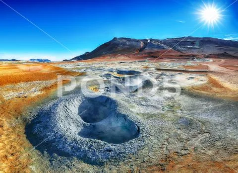 Boiling mudpots in the geothermal area Hverir and cracked ground around. Stock Photos