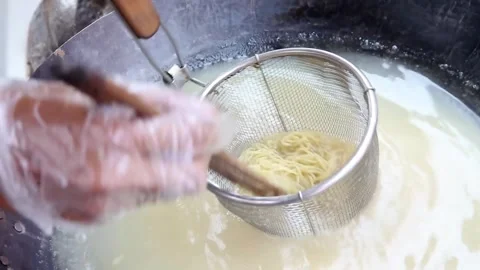 Boiling noodles using a noodle strainer while stirring with chopsticks Stock Footage 272297403