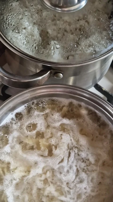Boiling Pasta in Metal Pot on Kitchen Stovetop Beside Steaming Rice Pot Stock-Footage 339080190