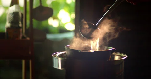 A boiling pot steams up as a restaurant's chef uses a ladle to stir soup Vídeos de archivo 274500411