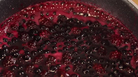 Boiling raspberry and blueberry sauce in a pot. Pan motion shot. Stock Footage 141931244