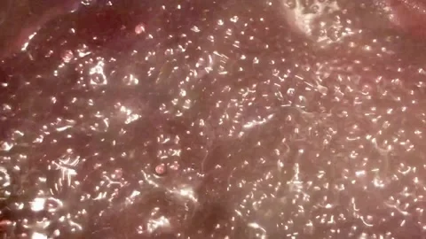 Boiling raspberry syrup caressed by steam bubbles and shimmers Stock Footage 136246793