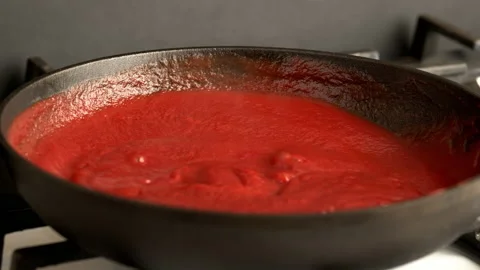 Boiling red tomato sauce cooked in a cast-iron frying pan. Tomato sauce is mixed Video stock 136664593