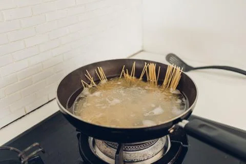 Boiling spaghetti with the pan in white kitchen. Stockfoto's