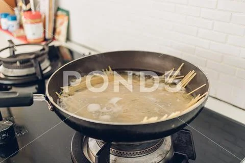 Boiling spaghetti with the pan in white kitchen. Stock Photos