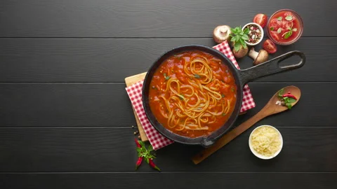 Boiling spaghetti with tomato sauce in cast iron pan served with chili pepper Stock Footage 131181421