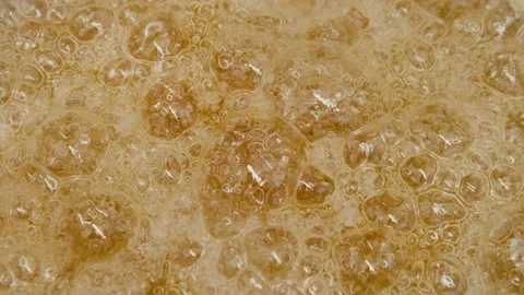 Boiling sugar turns into caramel. Close-up of caramel sauce bubbles in a bowl Stockbeeldmateriaal 197685285