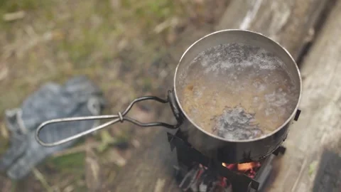 Boiling tea in camping pot standing on portable folding wood stove in forest. Stock Footage 280226838