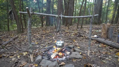 Boiling tea kettle, pot hanger over Campfire Survival Bushcraft Lean to Shelter. Stock Footage 118710658