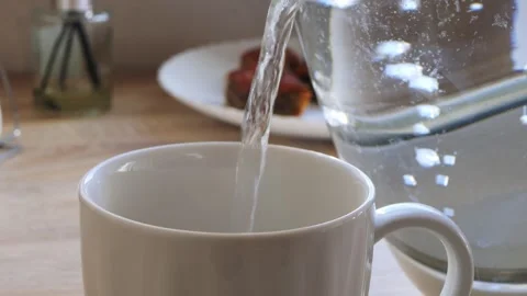 Boiling water from a kettle is poured into a cup on a table. Medium shot. Stock Footage 314574294