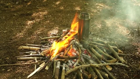 Boiling Water over the Campfire. Boiling Water in Metal Bottle for Survival Stock Footage 306871470